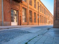 an empty side walk lined with buildings on a sunny day of the day with sunlight in it