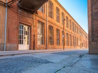 an empty side walk lined with buildings on a sunny day of the day with sunlight in it