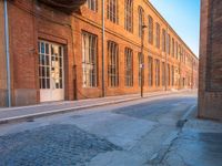 an empty side walk lined with buildings on a sunny day of the day with sunlight in it