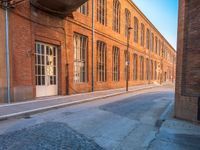 an empty side walk lined with buildings on a sunny day of the day with sunlight in it