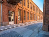 an empty side walk lined with buildings on a sunny day of the day with sunlight in it