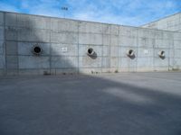 the empty parking lot in front of a wall with apartment buildings on it and a skateboarder on a ramp