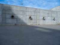 the empty parking lot in front of a wall with apartment buildings on it and a skateboarder on a ramp