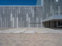 a white building with several steps and large glass panels in the facade is a mosaic that depicts a man