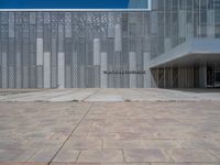 a white building with several steps and large glass panels in the facade is a mosaic that depicts a man