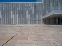 a white building with several steps and large glass panels in the facade is a mosaic that depicts a man