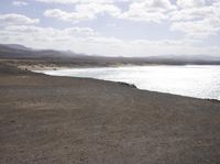 a view of the ocean from a barren hill top with the beach in the distance