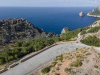 there is a motorcycle riding on the steep mountain path that leads to a cove with sea view