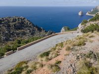 there is a motorcycle riding on the steep mountain path that leads to a cove with sea view