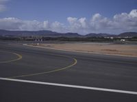 a airport runway with the view of hills in the distance and empty fields and empty road