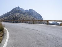 a motorcyclist is riding on the side of the road with a mountain in the background