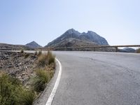 a motorcyclist is riding on the side of the road with a mountain in the background