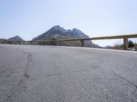 a motorcyclist is riding on the side of the road with a mountain in the background