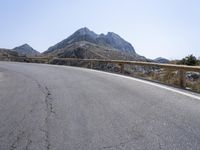 a motorcyclist is riding on the side of the road with a mountain in the background