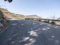 a scenic road curves along side a hillside and a hill, looking up at the sky