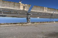 large solar array sitting on top of dirt field next to water and a street light