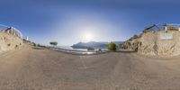 a fish eye view of an empty street with parked cars on it and the sun reflecting off the mountain