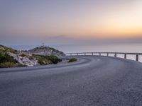 winding asphalt roadway near sea and cliffs on the horizon with sunset in the sky above