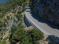 a car is driving on the road up the hill side, looking down at the road from above