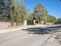 a paved road with a gate and several bushes near the side of it near a park