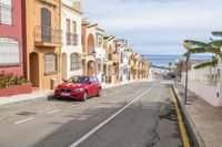 a street with an alley next to a red car and a beachside building next to it