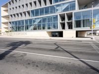 a modern building with huge windows is near a cross walk intersection on the street corner
