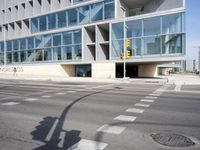 a modern building with huge windows is near a cross walk intersection on the street corner