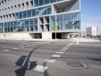 a modern building with huge windows is near a cross walk intersection on the street corner