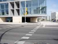 a modern building with huge windows is near a cross walk intersection on the street corner