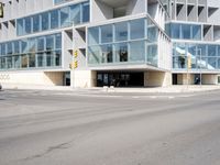 a modern building with huge windows is near a cross walk intersection on the street corner