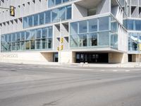 a modern building with huge windows is near a cross walk intersection on the street corner