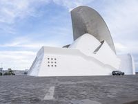 a car is parked in front of a building with curved concrete roofs and doors and a circular roof