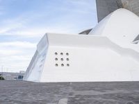 a car is parked in front of a building with curved concrete roofs and doors and a circular roof