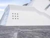 a car is parked in front of a building with curved concrete roofs and doors and a circular roof