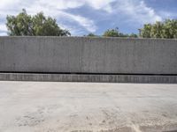 a concrete wall and roadway with trees in the distance behind it in front of a building