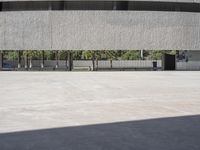 a concrete building with benches and benches underneath it by the side of the street while a man skateboards