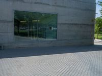 there is a stone wall that reflects the parking area in the window glass at the corner