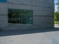 there is a stone wall that reflects the parking area in the window glass at the corner