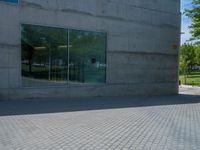 there is a stone wall that reflects the parking area in the window glass at the corner