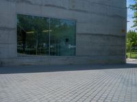 there is a stone wall that reflects the parking area in the window glass at the corner