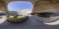 the view out the center of a curved concrete structure on top of a field of green grass