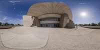 a fish eye view of a huge structure on a sunny day on a beach with blue skies