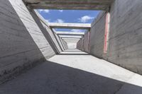 a concrete hallway with many doorways and concrete walls along side with a blue sky background