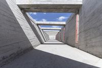 a concrete hallway with many doorways and concrete walls along side with a blue sky background