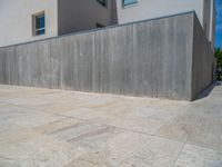 the gray concrete walls of a building have a line of steps on the left side