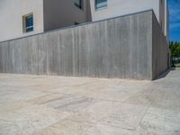 the gray concrete walls of a building have a line of steps on the left side