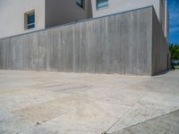 the gray concrete walls of a building have a line of steps on the left side