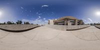 a photo taken in the reflection of a skateboard ramp with the sky and the sun shining in the background