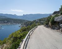 there is a motorcycle that is going up the hill on a curved road, overlooking the water