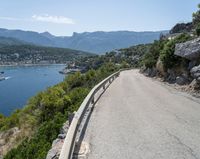 there is a motorcycle that is going up the hill on a curved road, overlooking the water